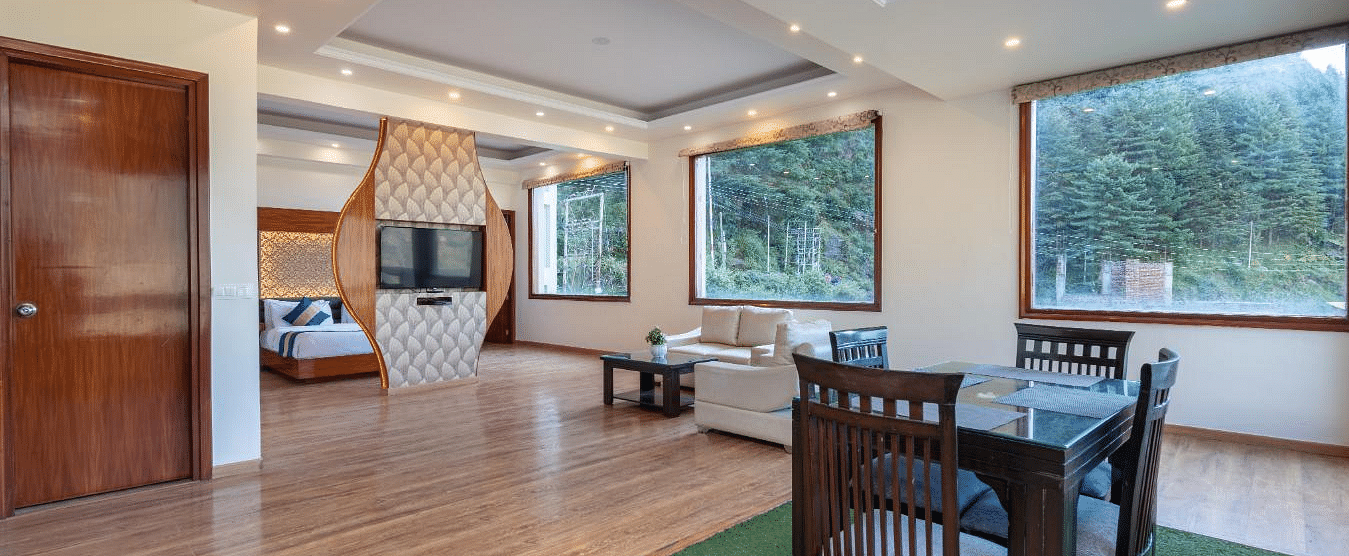 Image of a spacious suite with a dining area, a sitting area with a sofa, and large windows offering scenic views  | DLS Serenity Resort and Spa